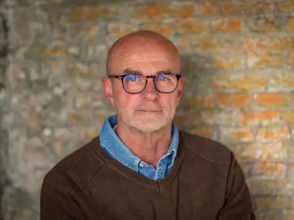 Portret van een persoon met bril voor een bakstenen muur.