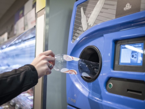 Hand plaatst een lege plastic fles in een statiegeldautomaat.