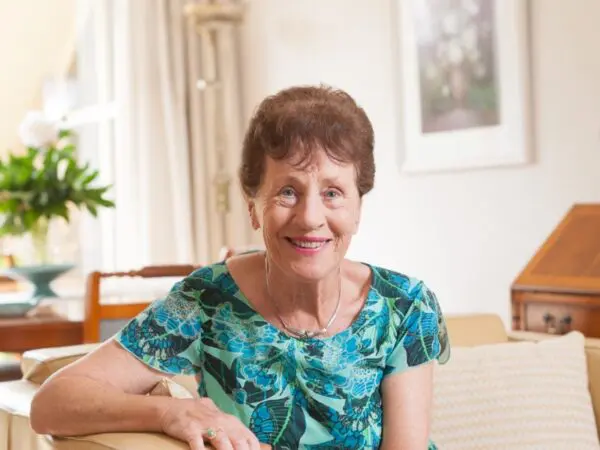 Portret van een persoon zittend op een bank in een woonkamer.